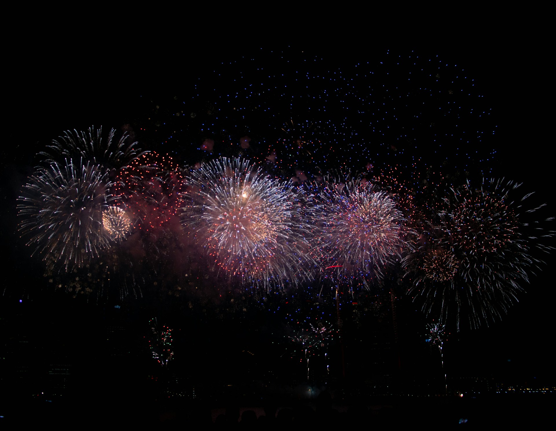 Red, white, and blue fireworks bursting over a dark night sky for the Semiquincentennial